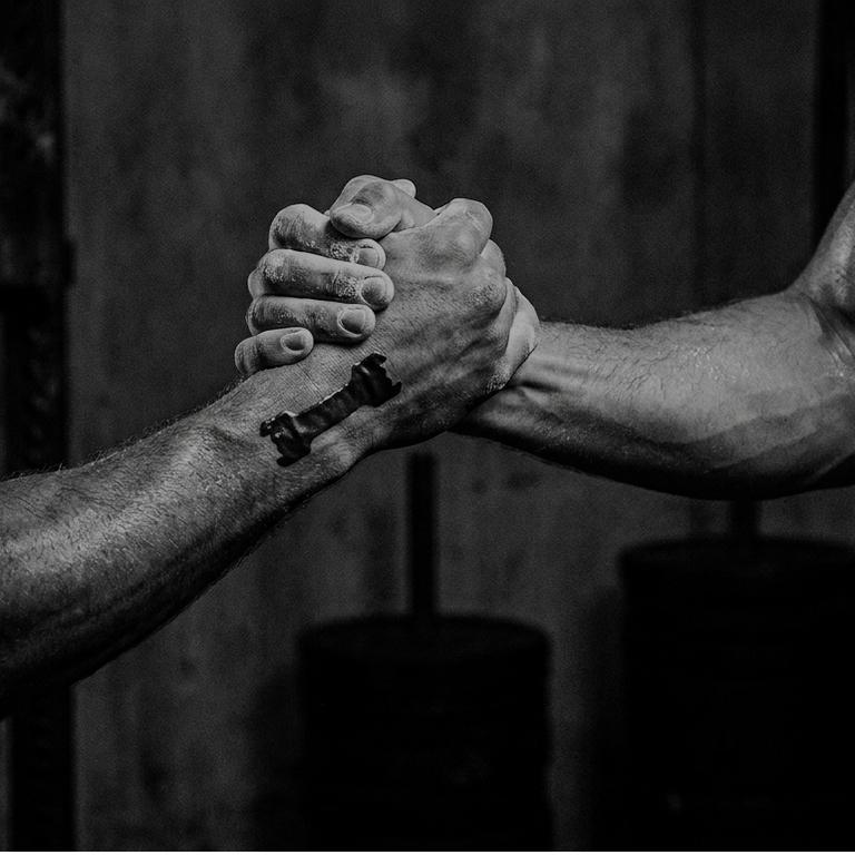 Two muscular arms shaking hands in a gym setting