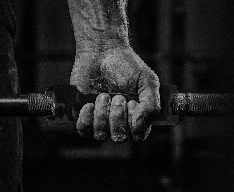 Black and white image of a hand gripping a barbell.